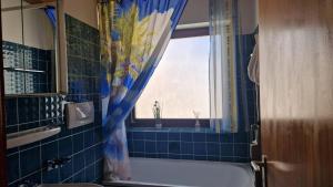 uma casa de banho com uma banheira e um chuveiro com uma janela em Haus Lucia em Schönwald