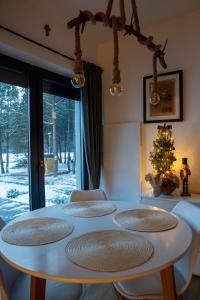Biały stół z 5 krzesłami i choinką świąteczną w obiekcie Domek Leśny Spokój Smyków w mieście Celiny