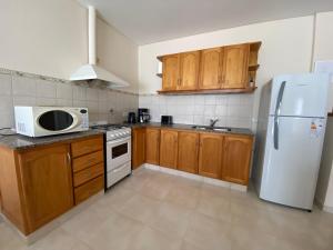 a kitchen with wooden cabinets and a white refrigerator at Loma Maria in Puerto Madryn