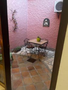 une table et des chaises devant un mur rose dans l'établissement Residencia Sofmel, à Copan Ruinas