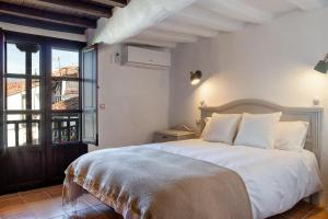 - une chambre avec un grand lit blanc et une fenêtre dans l'établissement Casa rural la grande, à Casas del Castañar