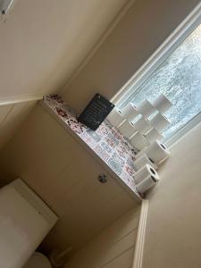 a small bathroom with a shelf next to a window at Spacious bright double room in London