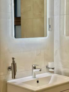 a bathroom with a sink and a mirror at Kensington House by Solitaire Suites in Slough