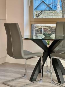 a glass table and two chairs in a room at Kensington House by Solitaire Suites in Slough