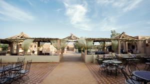 an outdoor patio with tables and chairs and tables and chairs at Auberge Sahara Garden in Lac Yasmins