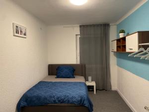 a small bedroom with a bed with a blue blanket at Ferienwohnung in Saarbrücken in Riegelsberg