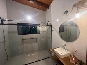a bathroom with a shower and a sink and a mirror at Paradouro Monã in Torres