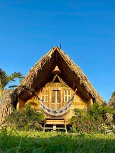 a thatched house with a hammock in front of it at Guajira Beach in Ríohacha
