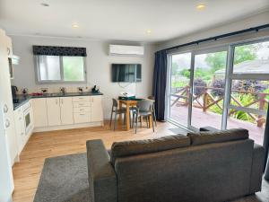 a living room with a couch and a table and a kitchen at Hideaway of Rotorua in Rotorua