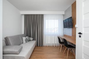 a living room with a couch and a desk at Gorczański Zakątek Jacuzzi & Sauna in Niedźwiedź