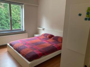 a bedroom with a bed with a colorful comforter and a window at Charming Sunny 100m2 Entire Apartment with 2 bedrooms in Brasschaat