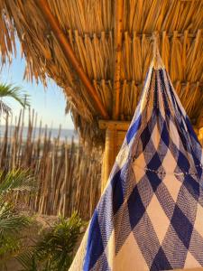 a blue and white checked bag hanging from a straw hut at Guajira Beach in Ríohacha