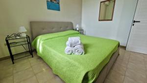 Case Vacanze Porto Vecchio في لامبيدوسا: غرفة نوم بسرير اخضر عليها مناشف