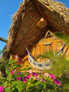 une cabane en paille avec un hamac en face de celle-ci dans l'établissement Guajira Beach, à Ríohacha