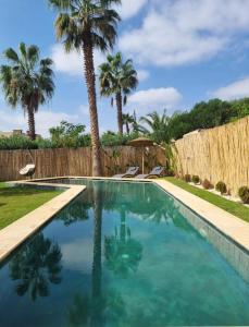 a swimming pool with palm trees and a fence at Villa Naya et sa Piscine chauffée sans vis-à-vis in Agadir