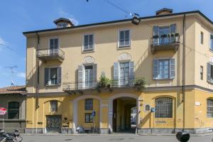 Mortara Navigli Apartments في ميلانو: مبنى اصفر مع نوافذ وشرفات على شارع