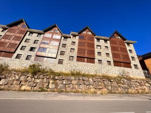 un gran edificio con una pared de piedra junto a una calle en Formigal Valle del tena Rural Home en Formigal