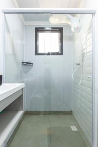 uma casa de banho branca com um chuveiro e um lavatório. em Chalé Container do Beijo em Campos de Jordão