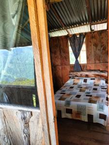 Ce lit se trouve dans une chambre en bois dotée d'une fenêtre. dans l'établissement Sierra de viboral adventures, à Medellín