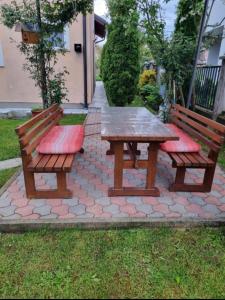 two benches and a wooden picnic table with red cushions at APRTMAN SARAJEVO ZA DVIJE OSOBE in Sarajevo