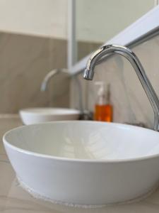 lavabo blanco con grifo en el baño en Casa Elenita, en San Juan La Laguna