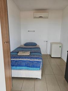 a small bedroom with a bed with a blue blanket at Warrawong on the Darling Wilcannia Holiday Park in Wilcannia