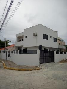 un immeuble d'appartements blanc avec un mur blanc dans l'établissement Casa 100m da praia, 10 pessoas, 3 quartos, à Bombinhas