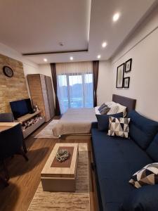 a living room with a blue couch and a bed at Apartmani L6 & P90 Milmari Kopaonik in Kopaonik