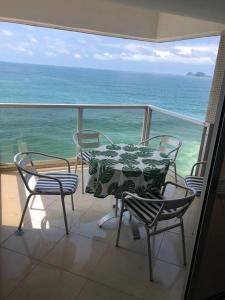 d'une table et de chaises sur un balcon donnant sur l'océan. dans l'établissement Apto Pitangueiras vista para o Mar, à Guarujá