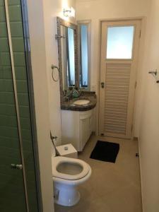 La salle de bains est pourvue de toilettes, d'un lavabo et d'un miroir. dans l'établissement Apto Pitangueiras vista para o Mar, à Guarujá