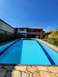 una piscina de agua azul frente a una casa en Pousada Aconchego 2 en Miguel Pereira