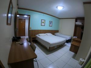 a bedroom with a bed and a desk and a table at Suíte Grand Hotel Dolphin in Caldas Novas