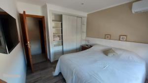 a bedroom with a white bed and a mirror at La Maruca 631 in Balcarce