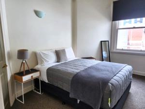 Schlafzimmer mit einem Bett und einem Fenster in der Unterkunft U Suites on Manners in Wellington