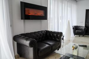 a black leather couch in a living room with a fireplace at Regal Guest House in Sighetu Marmaţiei
