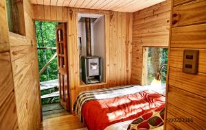 1 dormitorio con 1 cama en una cabaña de madera en Casita Arbol, en Puerto Fuy