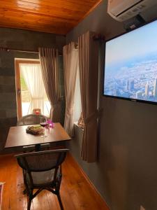 a room with a table and a large tv on the wall at Keshtjella Xhabeqos Rooms in Tirana