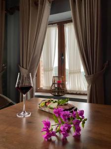 a table with a glass of wine and flowers on it at Keshtjella Xhabeqos Rooms in Tirana