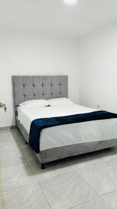 uma cama grande num quarto branco com uma parede branca em Apto con parqueadero Escalini Mansión Puerta del sol Pitalito em Pitalito