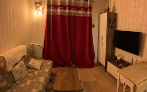 ein Wohnzimmer mit einem Sofa und einem roten Vorhang in der Unterkunft Studio 5 couchages SCHUSS 5 la foux d’allos in Allos