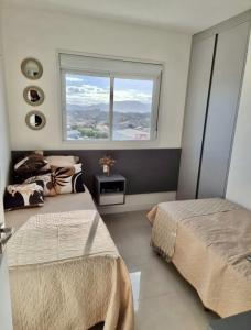 - une chambre avec 2 lits et une fenêtre dans l'établissement Apto decorado e bem localizado, à Capão da Canoa