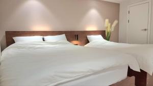 two beds in a bedroom with white sheets at Classic LeeYou in Seoul