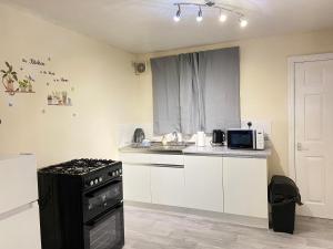 a small kitchen with a stove and a microwave at Kisobi Home Bedroom 1 in Hull