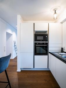 a kitchen with white cabinets and a black oven at Whirlpool - zentral - Designloft mit XXL Terrasse in Wiesbaden