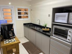 a kitchen with a microwave oven and a sink at Apto Beira Mar 3D in Capão da Canoa
