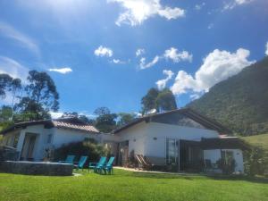 ein weißes Haus mit blauen Stühlen im Hof in der Unterkunft linda finca bien ubicada clima primaveral in Fredonia