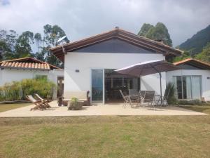 ein weißes Haus mit einer Terrasse mit Stühlen und einem Sonnenschirm in der Unterkunft linda finca bien ubicada clima primaveral in Fredonia