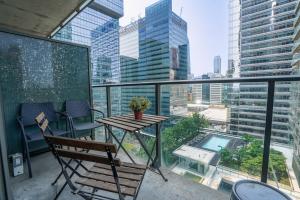 a balcony with a table and chairs and a view of a city at Simply Comfort Suites - One plus Den Apartment with Scotiabank Arena View in Toronto