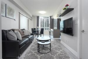 uma sala de estar com um sofá preto e uma mesa em Simply Comfort Suites - One plus Den Apartment with Scotiabank Arena View em Toronto