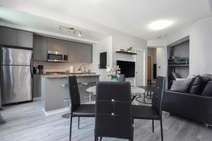 a kitchen and living room with a table and chairs at Simply Comfort Suites - One plus Den Apartment with Scotiabank Arena View in Toronto